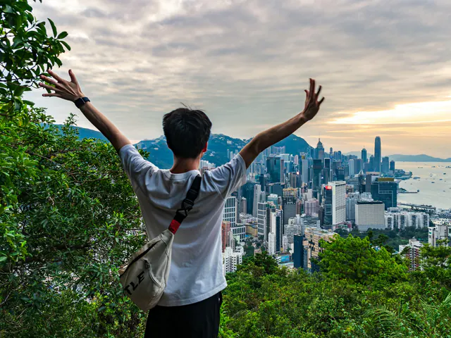 A traveller with arms raised above a city skyline